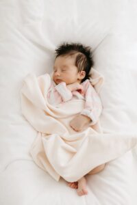 A newborn girl sleeping in a white blanket