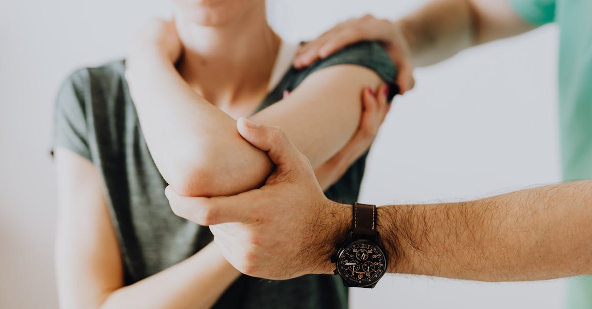 Crop unrecognizable chiropractor examining arm joint of female patient