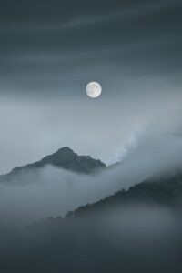 Full Moon over Foggy Mountains Covered With Clouds