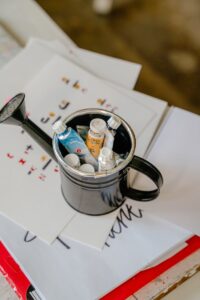 Tubes of paints in watering can and sheets of paper