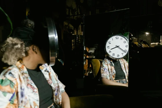 Woman Sitting in front of a Mirror with a Clock Dial Covering Her Face