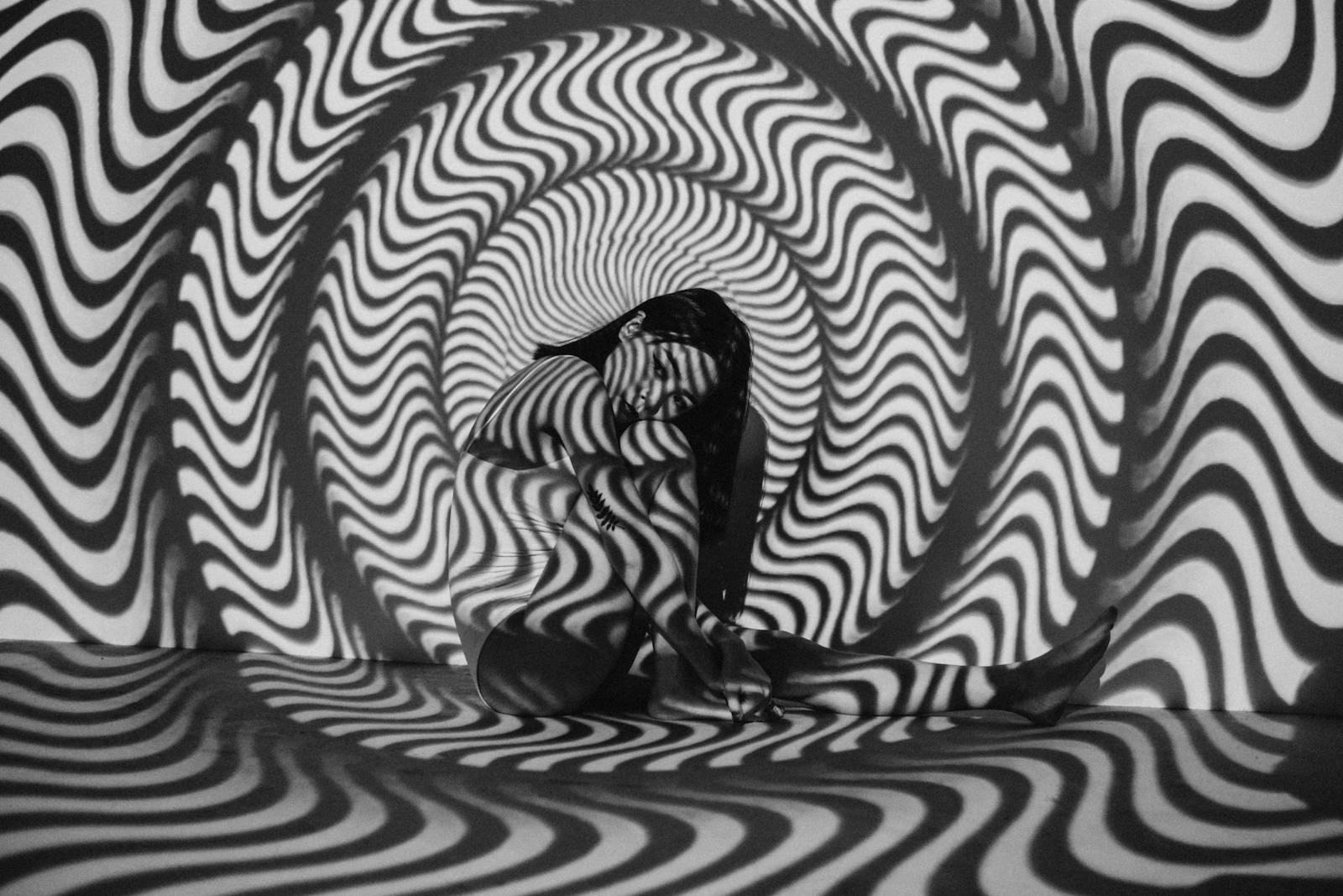 A woman enveloped in a trippy black and white optical illusion, creating a striking visual effect.