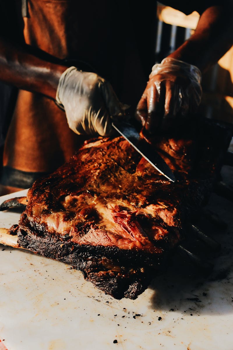 A skilled chef slices roasted steak on a barbecue grill, showcasing culinary expertise and deliciousness.